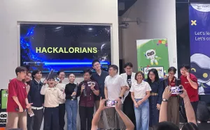 The Hackalorians team celebrates on stage with mentors, organizers, and event speakers after receiving recognition during the DevCon Kids AI Hackathon, posing for photos in front of the event display.