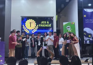 The Jes & Friends team celebrates their first-place victory at the DevCon Kids AI Hackathon, posing with mentors, organizers, and event hosts while holding their awards during the recognition ceremony.